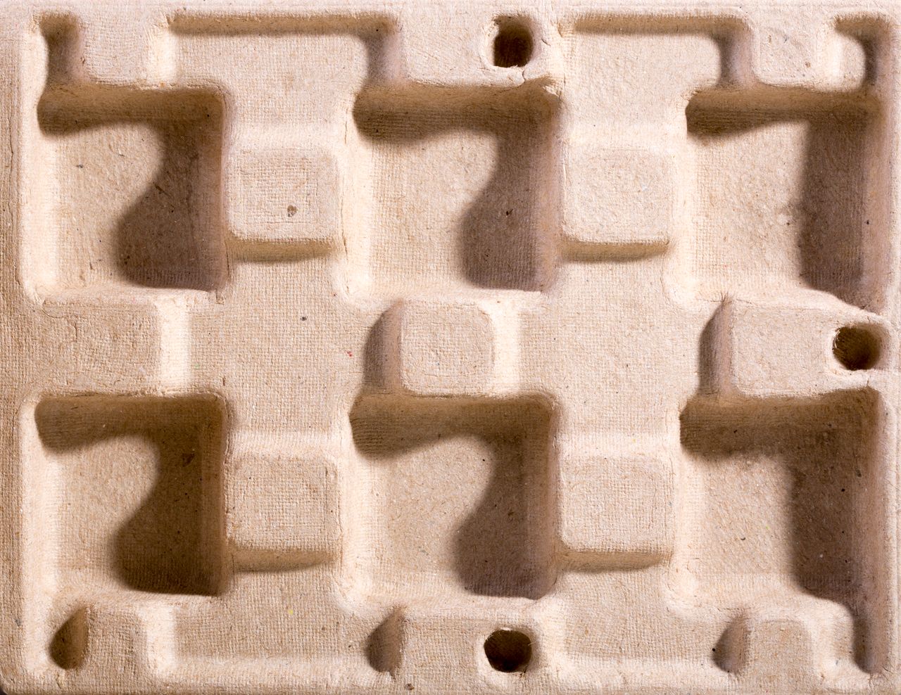 Close-up of an eco-friendly molded fiber packaging material with geometric indentations.